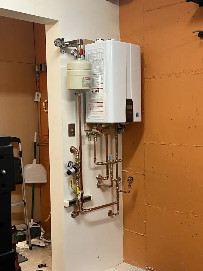 Plumbing technician inspecting water heater connections in Barberton